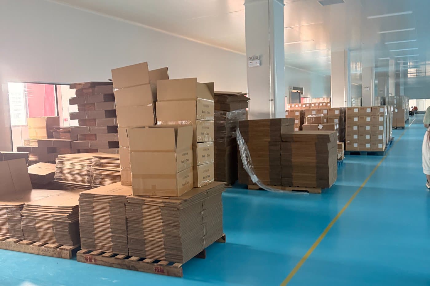 Cartons and palletised goods in an aisle on a supplier's floor in Shenzhen.
